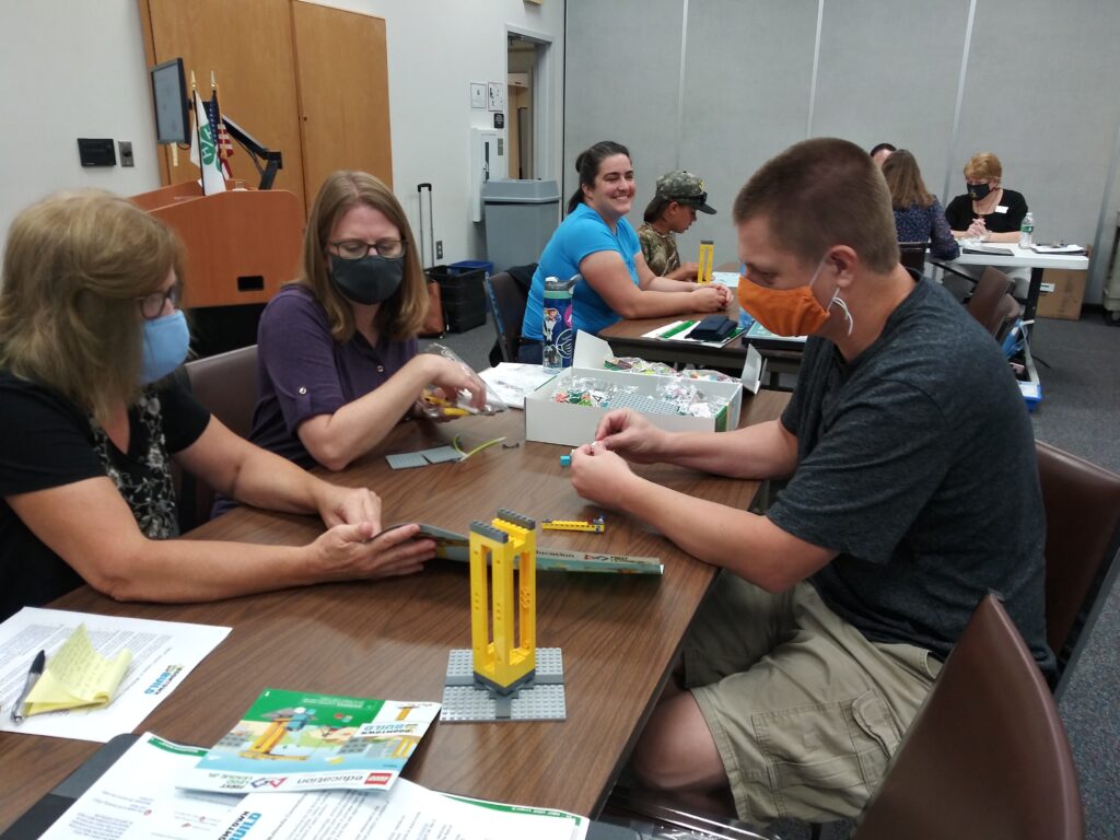 Three people around table with lego pieces