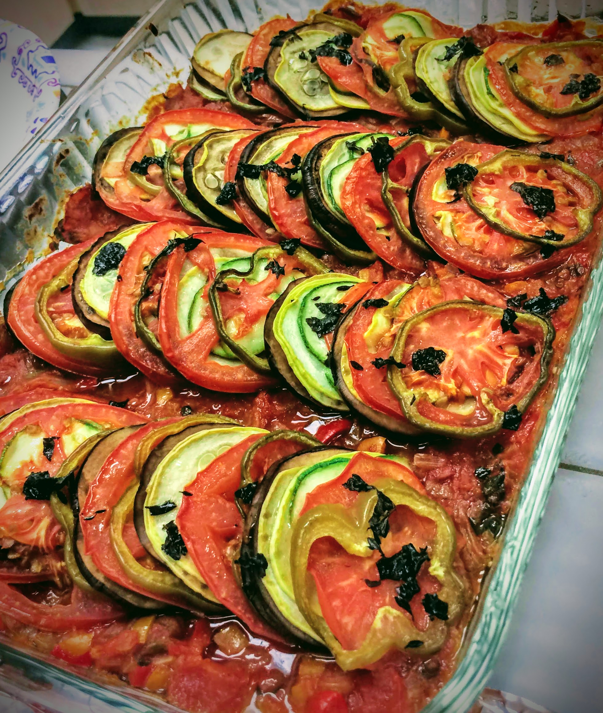 baked ratatouille. Layers of eggplant, tomatoes, peppers with basil sprinkled over.